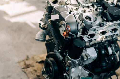 Close-up of a car engine showcasing intricate mechanical parts and details in a workshop setting.